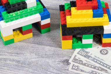 Renkli oyuncak blokları ve dolar banknotlarından yapılmış küçük evler. Konut maliyetleri konusu