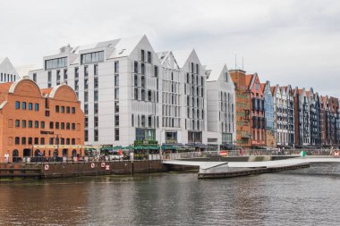 Gdansk, Polonya - 25 Ağustos 2023: Polonya 'nın merkezindeki Motlawa nehri üzerindeki köprü, gezinti güvertesi ve modern binalara bakın