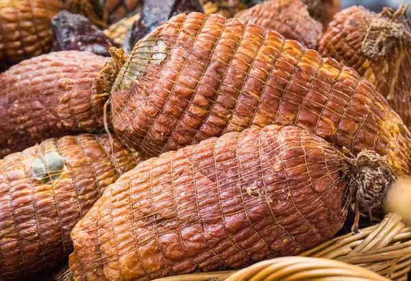 Fresh prepared smoked hams with spices in wicker basket on market stall or in grocery shop