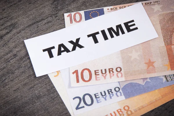 Inscription tax time and euro banknotes. Time of calculating, return or tax payment. Wooden background