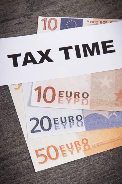 Inscription tax time and euro banknotes. Calculating and paying tax for previous year. Wooden background