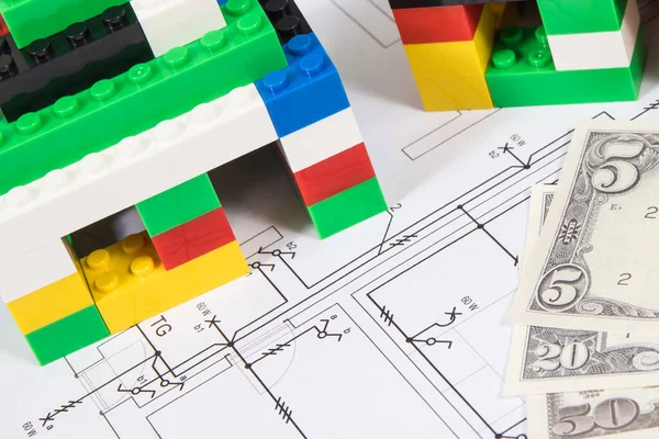 Small houses made of colorful toy blocks, housing plan with electric installation and dollar banknotes. Subject of building or renting home