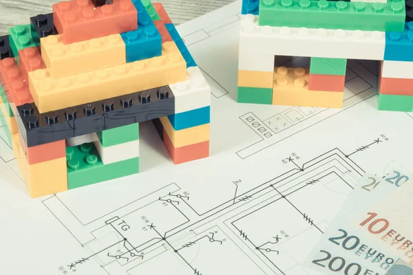 Small houses made of colorful toy blocks, housing plan with electric installation and euro banknotes. Subject of building or renting home