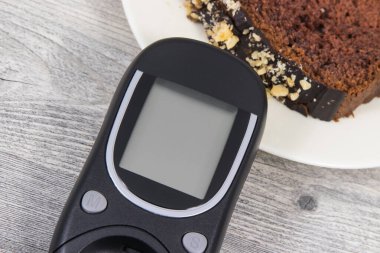 Glikoz ölçer ve tatlı çikolatalı pasta. Diyabet sırasında şeker seviyesini ölçmek ve kontrol etmek