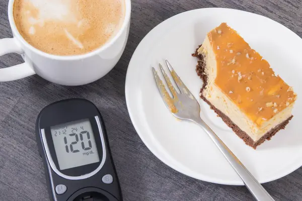 Glucose meter with high result of measurement sugar level, portion of sweet cheesecake and cup of coffee with milk. Nutrition during diabetes concept