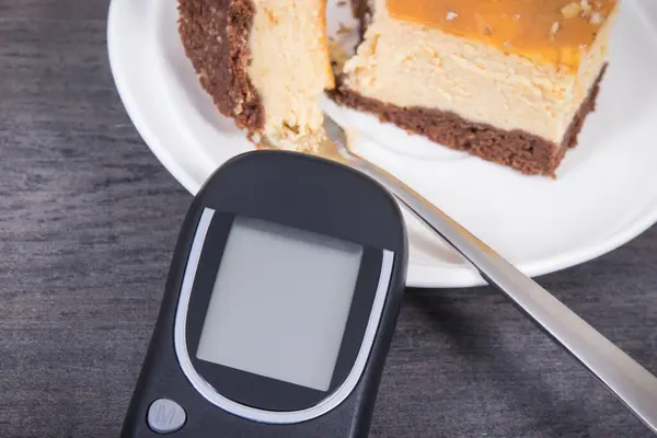 Glucose meter and fresh baked sweet cheesecake. Measuring and sugar level control during diabetes