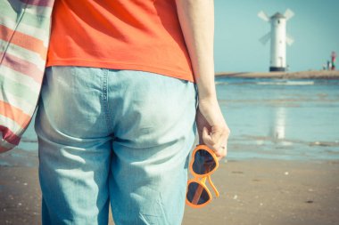 Swinoujscie 'nin batı dalgasında kalp şeklinde güneş gözlüklü bir kadın. Arka planda Windmill Stawa Mlyny karakteristik yön bulma işareti var. Yaz ve tatil zamanı