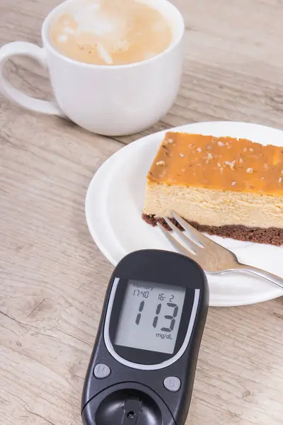 Glucometer with high result of measurement sugar level, portion of sweet cheesecake and cup of coffee with milk. Nutrition during diabetes concept