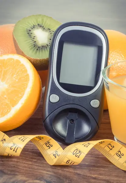 Glucose meter for measuring and checking sugar level, fresh ripe fruits and orange juice. Healthy lifestyle and nutrition during diabetes