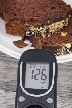 Glikoz ölçer, yüksek şeker seviyesi, tatlı çikolatalı pasta. Diyabet konsepti sırasında besin