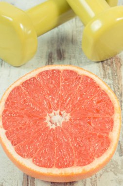 Zindelik için taze greyfurt ve dambıl. Sağlıklı bir yaşam tarzı. Kaynak mineraller ve vitaminler olarak meyveler