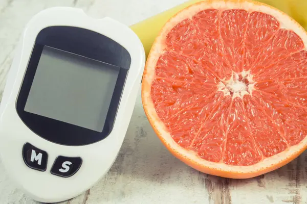 用于测量和检查糖分水平 新鲜成熟柚子和哑铃是否健康 糖尿病期间的健康生活方式和营养 免版税图库照片