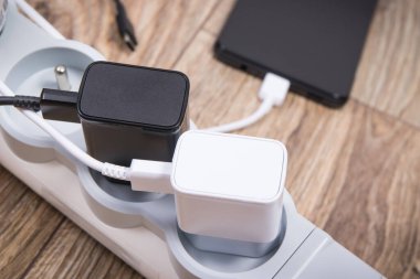 Siyah akıllı telefon, cep telefonu ve elektrik hattına bağlı şarj cihazları. Çeşitli aygıtlar şarj etme kavramı