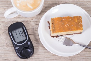 Glukometre, porsiyon tatlı cheesecake ve sütlü bir fincan kahve. Diyabet sırasında şeker seviyesini ölçmek ve kontrol etmek