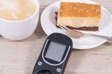 Glikoz ölçer, bir parça tatlı cheesecake ve sütlü bir fincan kahve. Diyabet sırasında şeker seviyesini ölçmek ve kontrol etmek
