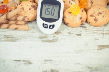 Glikoz ölçer, yüksek şeker seviyesi, şeker ve kurabiyeler. Sağlıklı yaşam tarzı, beslenme ve diyabet sırasında şeker yeme azalması. Metin için yer