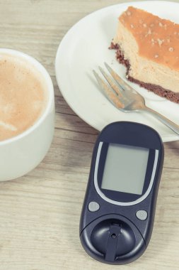 Şeker seviyesini ölçmek için glukometre, tatlı cheesecake ve sütlü kahve. Diyabet konsepti sırasında besin