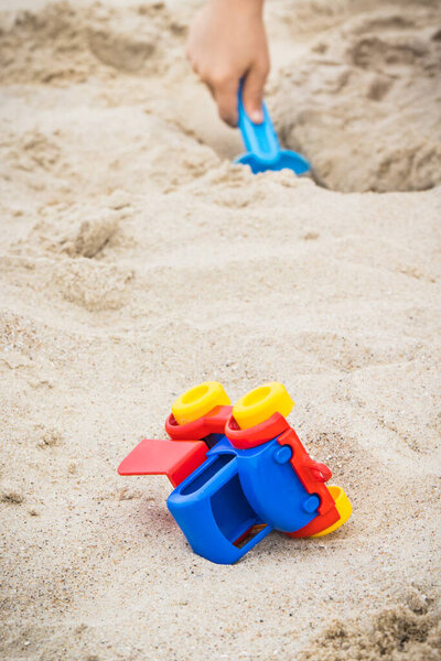Мальчик с пластиковыми детскими игрушками на песке на пляже. Расслабься или играй летом. Время отпуска