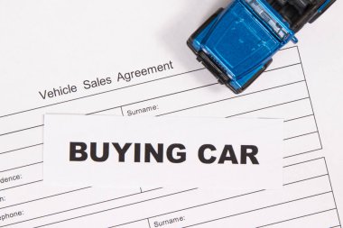 Küçük mavi oyuncak araba ve bir çeşit araç satış anlaşması. Araba satın alma yazıtları. Satışlar ve yeni ya da kullanılmış araba alımları