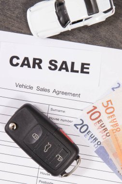 Küçük beyaz oyuncak araba, siyah araba anahtarı, euro banknotları ve araç satış anlaşması. Satışlar ya da alımlar yeni ya da kullanılmış araçlar. Ulaşım