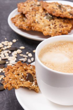 Sütlü kahve ve beyaz tabakta taze yulaf ezmeli kurabiye. Lezzetli çıtır tatlı.