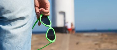 Swinoujscie 'nin batı dalgasında kalp şeklinde güneş gözlüklü bir kadın eli. Arka planda Windmill Stawa Mlyny karakteristik yön bulma işareti var. Yaz ve tatil zamanı