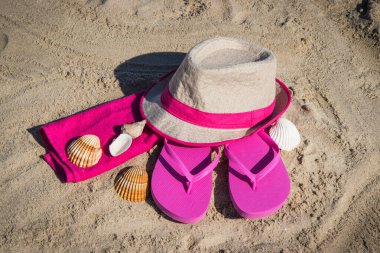 Kumsalda dinlenmek için aksesuarlar. Hasır şapka, pembe terlik ve kabarık havlu. Yaz zamanı.