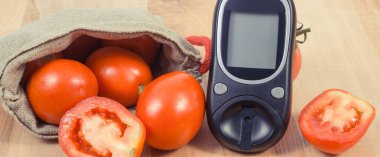 Şeker seviyesini ölçmek ve ölçmek için glukometre ve taze olgun domatesler. Diyabet sırasında sağlıklı yaşam tarzı ve beslenme