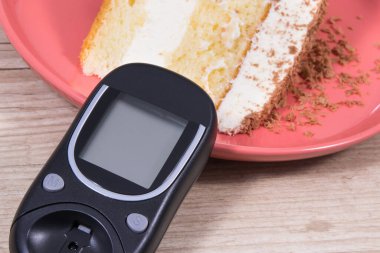 Şeker seviyesini ölçmek ve kontrol etmek için glukometre ve katmanlı ve çikolatalı tatlı pasta. Diyabet konsepti sırasında besin