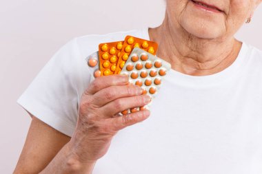 Elinde tablet ya da takviye malzemelerle yaşlı bir kadın. Tedavi ya da yaşlılıkta bağışıklığın güçlendirilmesi. Sağlık hizmetleri