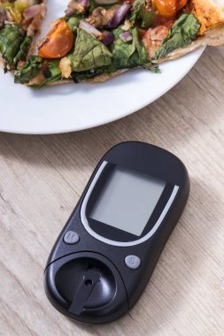 Glikoz ölçer şeker seviyesini taze pişmiş vejetaryen pizzayla ölçmek ve kontrol etmek için kullanılır. Diyabet konsepti sırasında besin