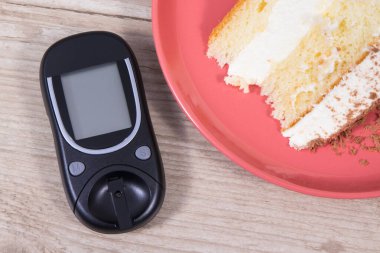 Şeker seviyesini ölçmek ve kontrol etmek için glukometre ve katmanlı ve çikolatalı tatlı pasta. Diyabet konsepti sırasında besin