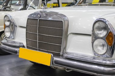 Poznan, Polonya - 07 Ekim 2023: Retro Motor Show. Poznan 'daki Uluslararası Fuar. Parlak eski klasik beyaz Mercedes W108 'in önünde bakın. Ayrıntı ve aracın parçası