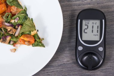 Glikoz ölçer şeker seviyesini kontrol etmek ve bir parça taze vejetaryen pizza için kullanılır. Diyabet konsepti sırasında beslenme ve fast food yeme