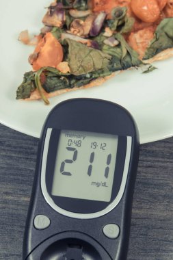 Glikoz ölçer, yüksek şeker seviyesi ve taze pişmiş vejetaryen pizzası sonucu oluşmuş. Diyabet konsepti sırasında besin