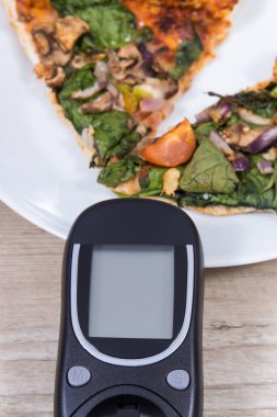 Glukometre şeker seviyesini taze pişmiş vejetaryen pizzayla ölçmek ve kontrol etmek için. Diyabet konsepti sırasında besin
