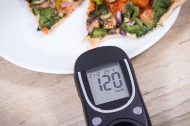Glikoz ölçer şeker seviyesini kontrol etmek ve bir parça taze vejetaryen pizza için kullanılır. Diyabet konsepti sırasında beslenme ve fast food yeme