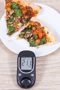 Glukometre, şeker seviyesi ve taze pişmiş vejetaryen pizzanın çok yüksek bir sonucu. Diyabet konsepti sırasında besin