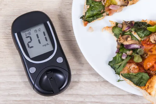 Glukometre, şeker seviyesi ve taze pişmiş vejetaryen pizzanın çok yüksek bir sonucu. Diyabet konsepti sırasında besin