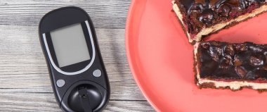 Şeker seviyesini ölçmek için kullanılan glukometre kirazlı ve çikolatalı fırında pişmiş cheesecake parçaları. Diyabet konsepti sırasında besin