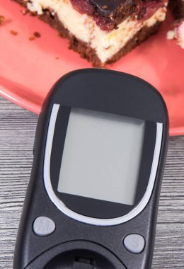 Şeker seviyesini ölçmek için kullanılan glukometre kirazlı ve çikolatalı fırında pişmiş cheesecake parçaları. Diyabet konsepti sırasında besin