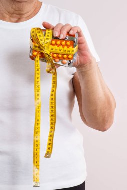 Elinde vitamin paketleri, takviyeler ve santimetre ile yaşlı bir kadın. Tedavi, zayıflama veya yaşlılıkta bağışıklığı güçlendirme. Sağlık hizmetleri