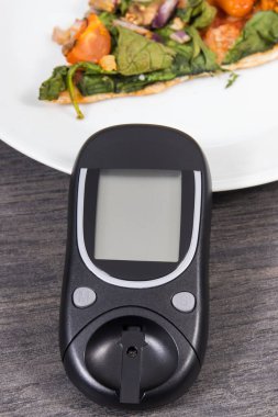 Glikoz ölçer şeker seviyesini taze pişmiş vejetaryen pizzayla ölçmek ve kontrol etmek için kullanılır. Diyabet konsepti sırasında besin