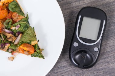Glikoz ölçer şeker seviyesini taze pişmiş vejetaryen pizzayla ölçmek ve kontrol etmek için kullanılır. Diyabet konsepti sırasında besin