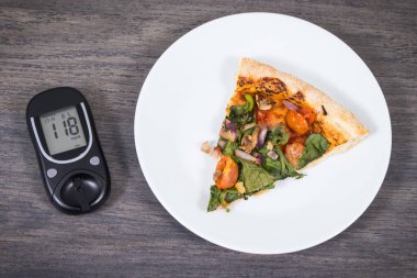 Glikoz ölçer şeker seviyesini kontrol etmek ve bir parça taze vejetaryen pizza için kullanılır. Diyabet konsepti sırasında beslenme ve fast food yeme