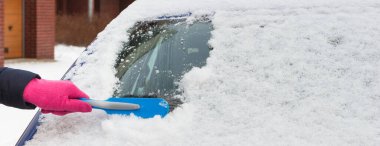 Hand using brush and remove snow from car and windscreen. Winter problems in transportation clipart