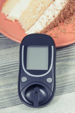 Glukometre, şeker seviyesini ölçmek ve bir parça çikolatalı tatlı kek için kullanılır. Diyabet konsepti sırasında sağlıklı yaşam tarzı