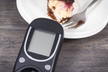 Şeker seviyesini ölçmek için kullanılan glukometre kirazlı ve çikolatalı cheesecake parçaları. Diyabet konsepti sırasında besin