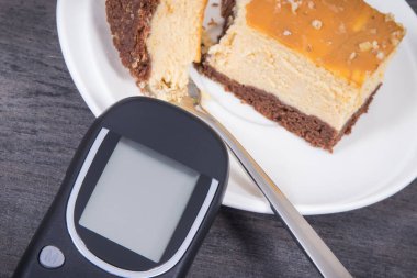 Glikoz ölçer ve taze pişmiş tatlı cheesecake. Diyabet sırasında ölçüm ve şeker seviyesi kontrolü
