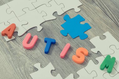 Otizm Spektrum Bozukluğunun sembolü olarak beyaz ve mavi bulmacaları, otizm yazıtlarını bir araya getiren çocuk eli. Otizm Farkındalık Günü konsepti